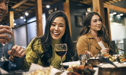 a group of people sitting at a table with food and drinks