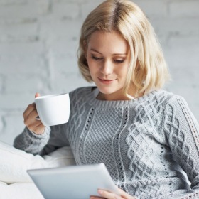 a woman holding a drink and a tablet